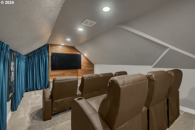 cinema with a textured ceiling, carpet flooring, wood walls, and vaulted ceiling