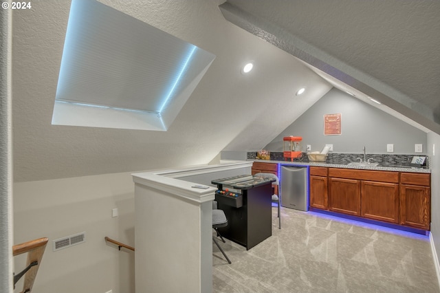 carpeted home office featuring sink, vaulted ceiling, and a textured ceiling