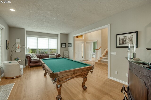 recreation room with a textured ceiling, light hardwood / wood-style floors, and billiards