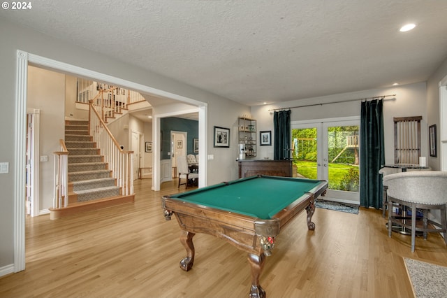 game room with french doors, pool table, a textured ceiling, and hardwood / wood-style floors