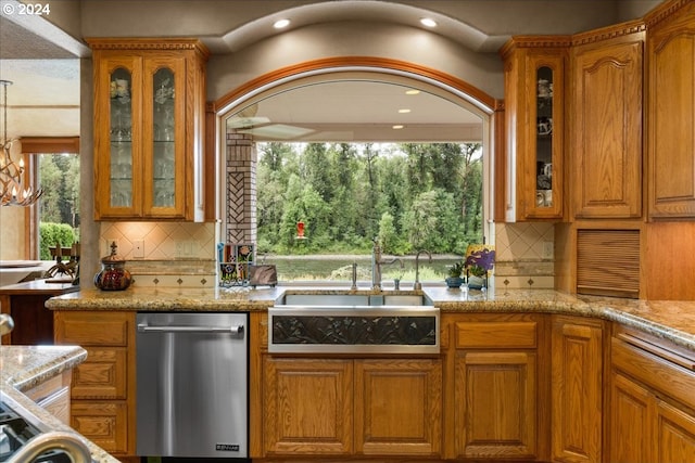 kitchen with sink, stainless steel dishwasher, tasteful backsplash, and light stone countertops