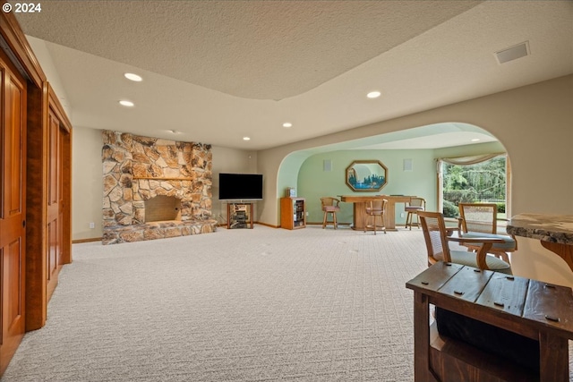 living room with a fireplace, a textured ceiling, and carpet flooring