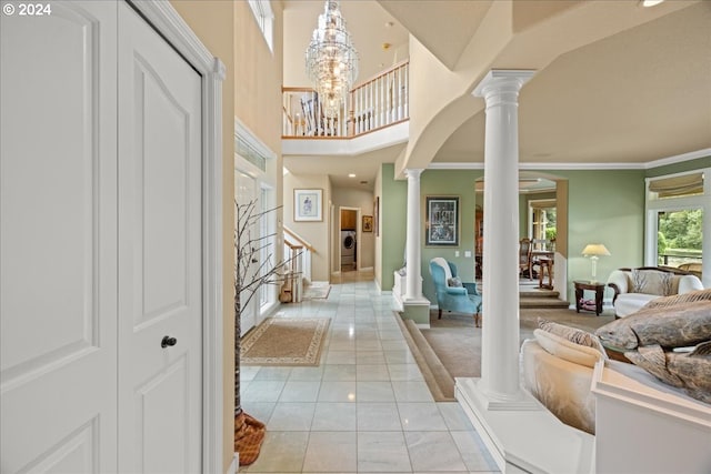 hallway featuring light tile patterned flooring, crown molding, a chandelier, and decorative columns