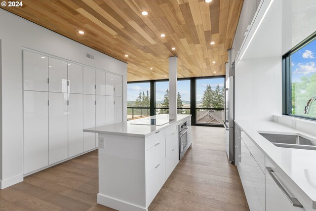 kitchen with white cabinetry, a healthy amount of sunlight, light wood-type flooring, and wooden ceiling