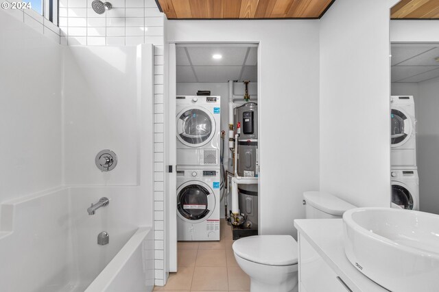 full bathroom with a drop ceiling, stacked washer and dryer, toilet, tile patterned flooring, and bathtub / shower combination