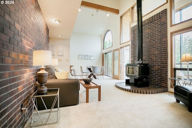 carpeted living room featuring brick wall, a wood stove, beam ceiling, and a towering ceiling