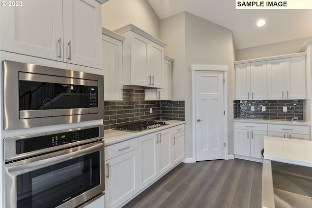 kitchen with tasteful backsplash, white cabinetry, stainless steel appliances, and dark hardwood / wood-style floors