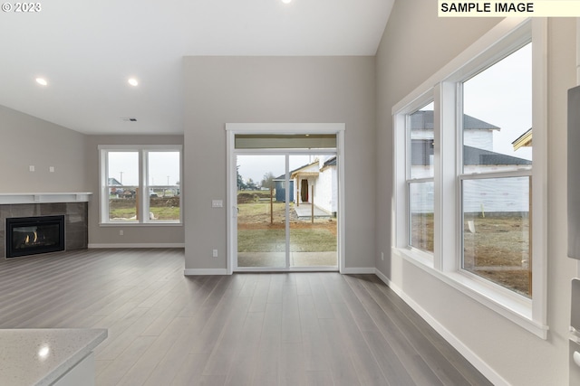 unfurnished living room featuring a tiled fireplace and wood-type flooring