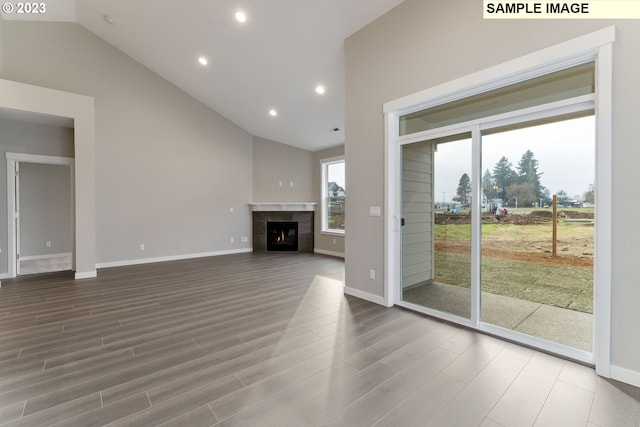 unfurnished living room with a tile fireplace, hardwood / wood-style floors, and vaulted ceiling