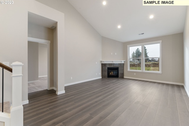 unfurnished living room with a tiled fireplace, dark hardwood / wood-style flooring, and vaulted ceiling