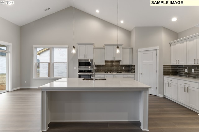 kitchen with high vaulted ceiling, decorative light fixtures, a healthy amount of sunlight, and appliances with stainless steel finishes