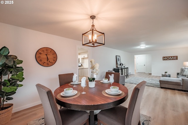 dining room with light wood-type flooring and an inviting chandelier