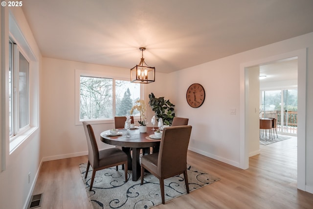 dining space featuring light hardwood / wood-style floors and an inviting chandelier