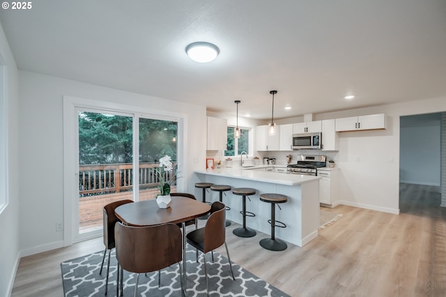 kitchen with appliances with stainless steel finishes, kitchen peninsula, pendant lighting, sink, and white cabinetry