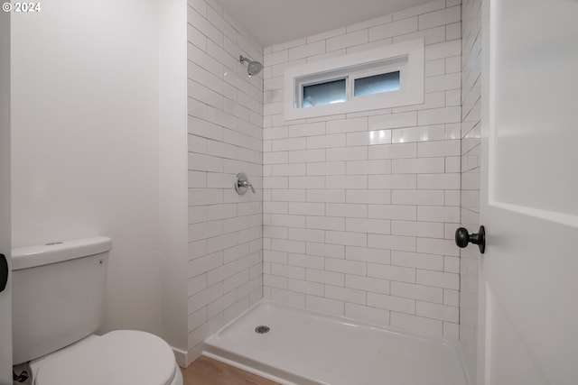 bathroom featuring tiled shower and toilet