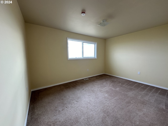 unfurnished room with dark colored carpet and baseboards