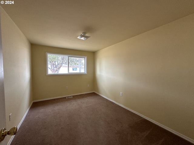 empty room featuring dark carpet and baseboards