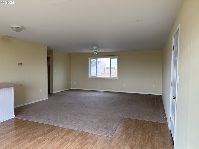 unfurnished room featuring baseboards, a ceiling fan, wood finished floors, and carpet flooring