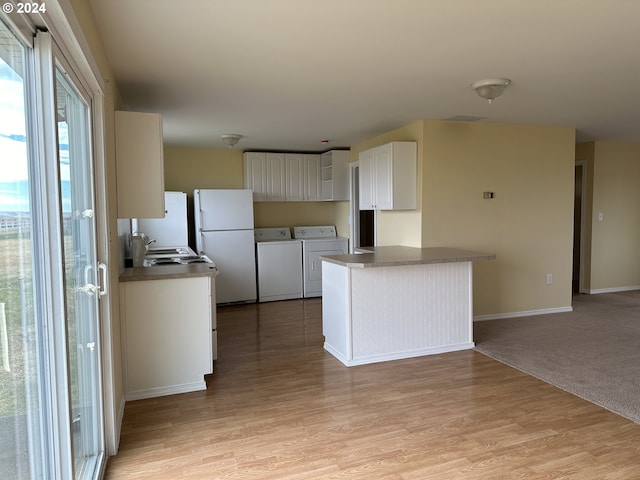 kitchen with freestanding refrigerator, white cabinets, washer and clothes dryer, light wood-style flooring, and baseboards