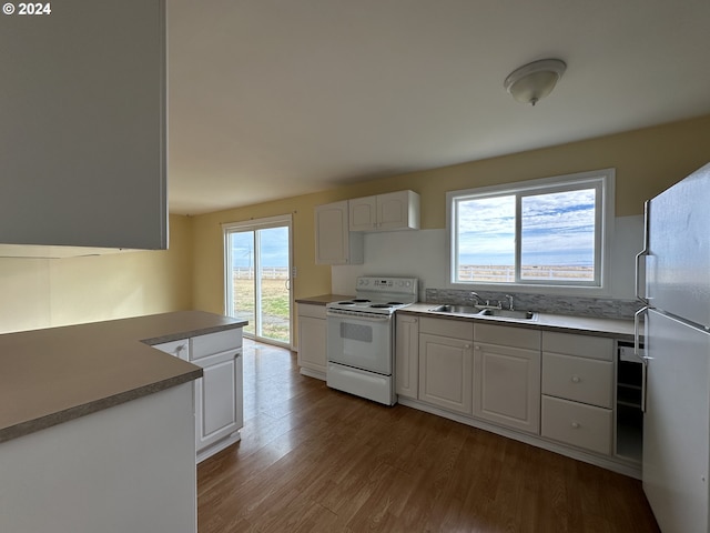 kitchen featuring white appliances, a sink, wood finished floors, white cabinets, and light countertops