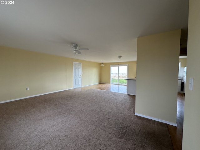 carpeted empty room featuring ceiling fan and baseboards