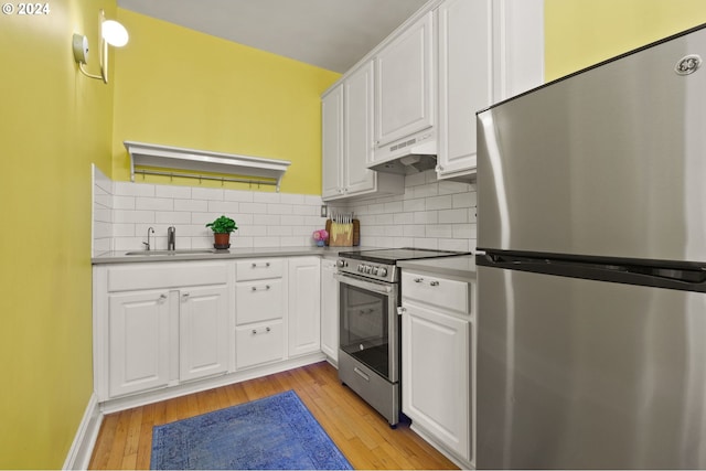 kitchen featuring appliances with stainless steel finishes, sink, custom exhaust hood, white cabinets, and light hardwood / wood-style flooring