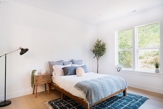 bedroom featuring multiple windows, visible vents, and light wood-style floors