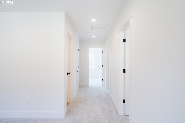 corridor featuring attic access, recessed lighting, light colored carpet, and baseboards