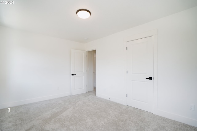 unfurnished bedroom featuring light carpet and a closet