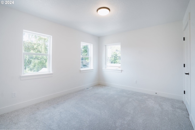 empty room with visible vents, baseboards, and light colored carpet