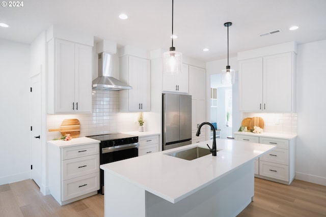 kitchen featuring backsplash, sink, an island with sink, light hardwood / wood-style floors, and stainless steel refrigerator