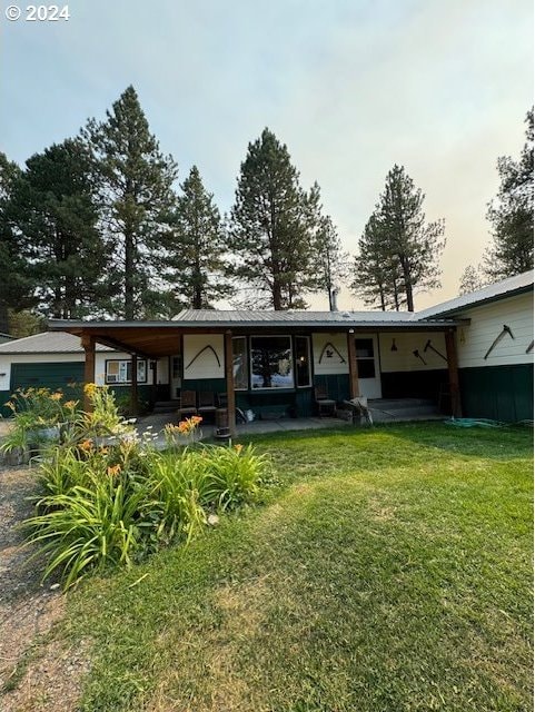 back house at dusk featuring a patio area and a lawn