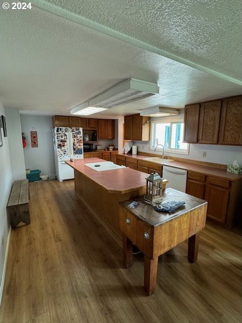 kitchen with a kitchen island, dark hardwood / wood-style floors, sink, and white appliances