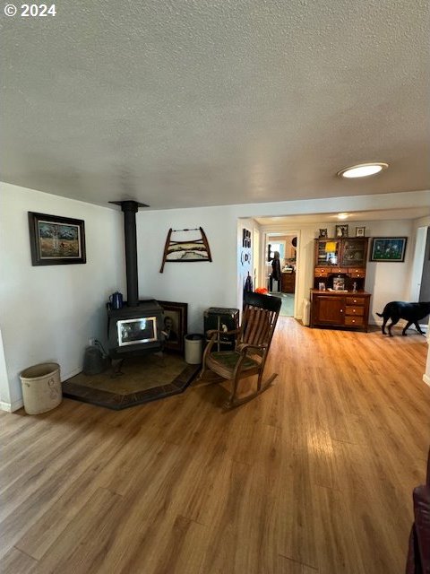 living room with hardwood / wood-style flooring, a textured ceiling, and a wood stove