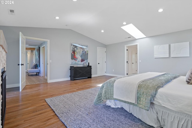 bedroom with lofted ceiling with skylight and hardwood / wood-style flooring