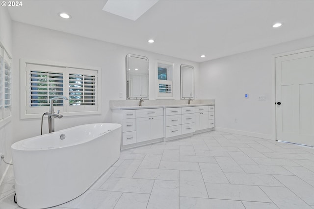 bathroom with a skylight, a bathtub, and vanity