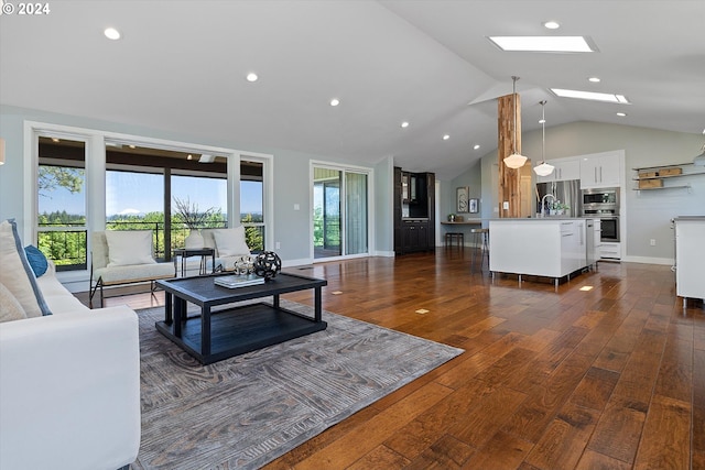 living room featuring lofted ceiling with skylight, plenty of natural light, dark wood-type flooring, and sink