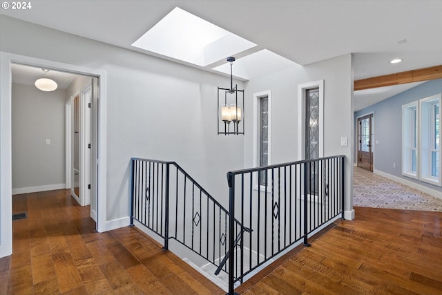 hall featuring an inviting chandelier, dark wood-type flooring, and a skylight