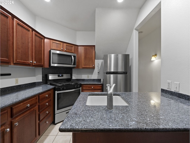 kitchen with a kitchen island, sink, stainless steel appliances, and dark stone counters