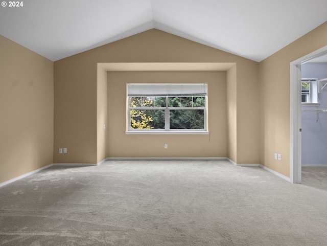 carpeted spare room featuring vaulted ceiling