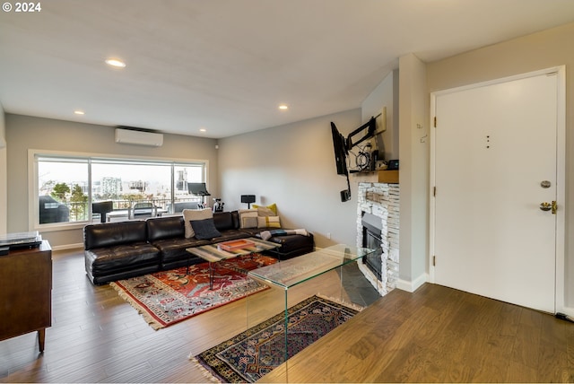 living room featuring wood-type flooring, a fireplace, and a wall mounted air conditioner