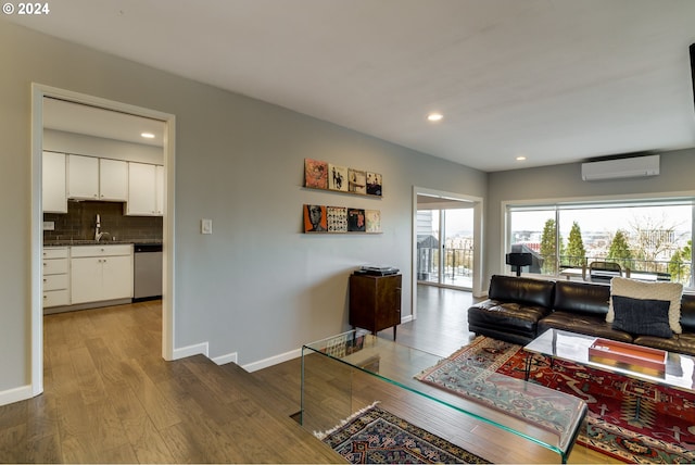 living room with wood-type flooring, sink, and a wall mounted air conditioner