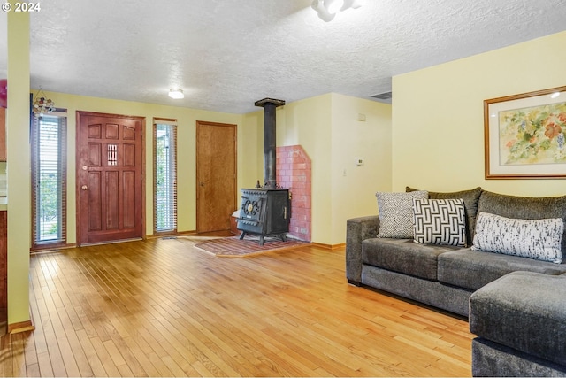 living room with a wood stove, a textured ceiling, and light wood-type flooring