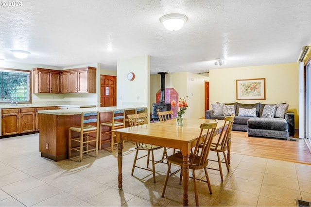 dining space with light hardwood / wood-style flooring, a wood stove, a textured ceiling, and sink