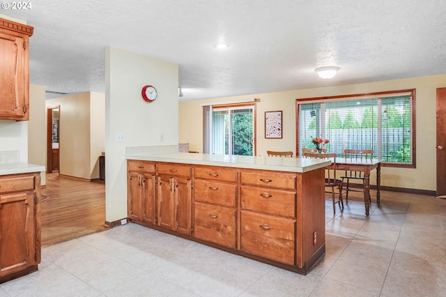 kitchen with light hardwood / wood-style floors, kitchen peninsula, and a textured ceiling