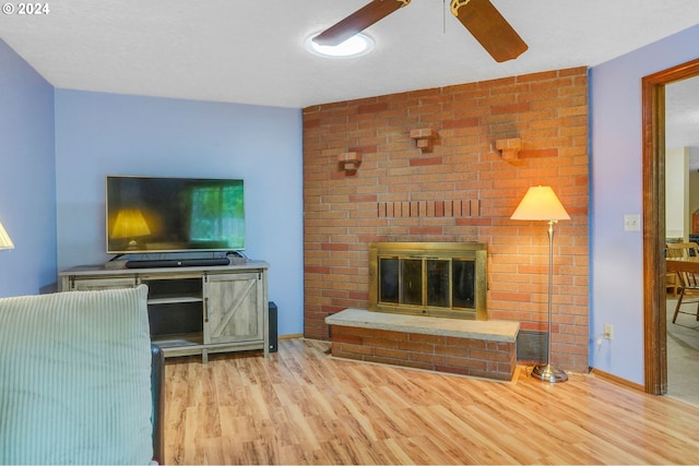 living room with light hardwood / wood-style floors, a fireplace, and ceiling fan