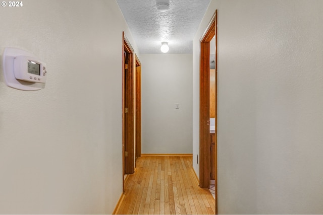 hallway featuring light hardwood / wood-style floors and a textured ceiling