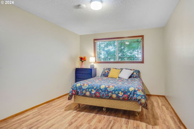 bedroom featuring light hardwood / wood-style flooring and a textured ceiling