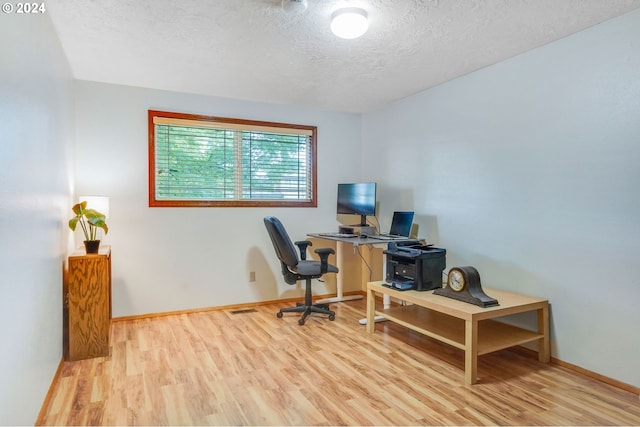 office featuring light wood-type flooring and a textured ceiling