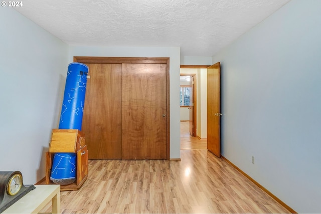 interior space with a textured ceiling, light hardwood / wood-style flooring, and a closet